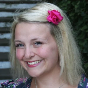 Colour portrait of Arlene, smiling, with pink flower hairclip